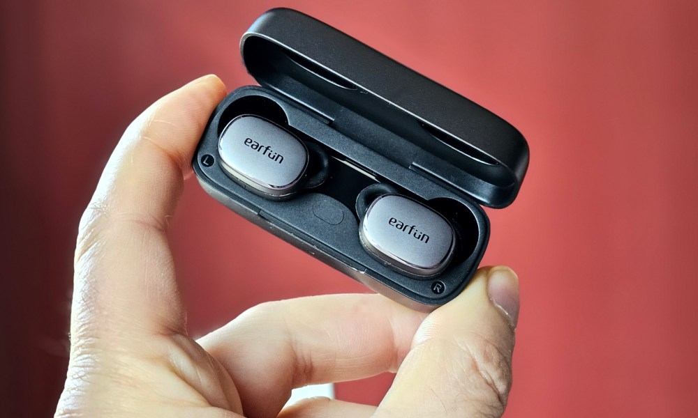 EarFun Free Pro 3 in charging case held in the air (lid open).