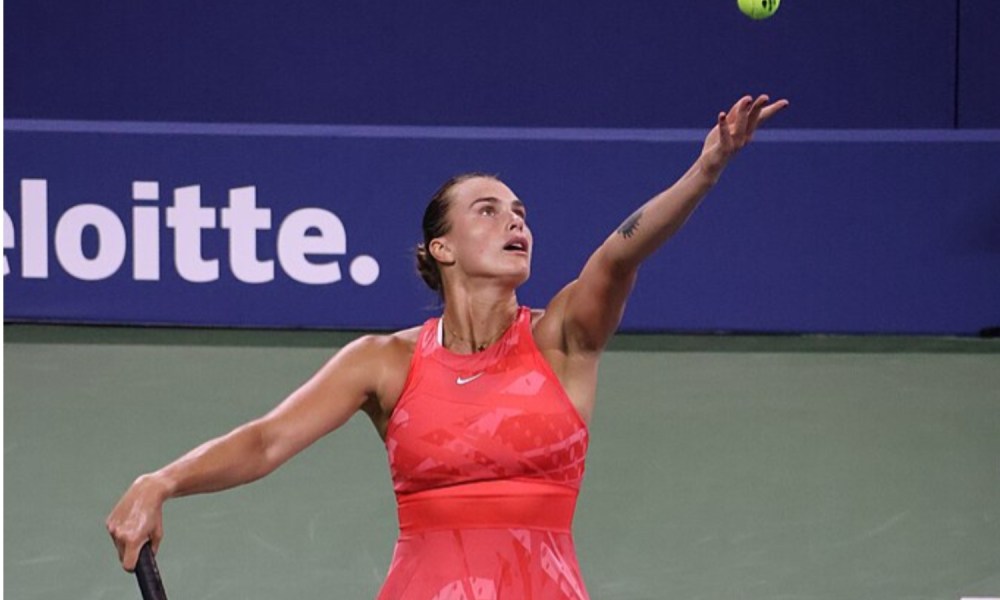 A female tennis player throws a tennis ball in the air.