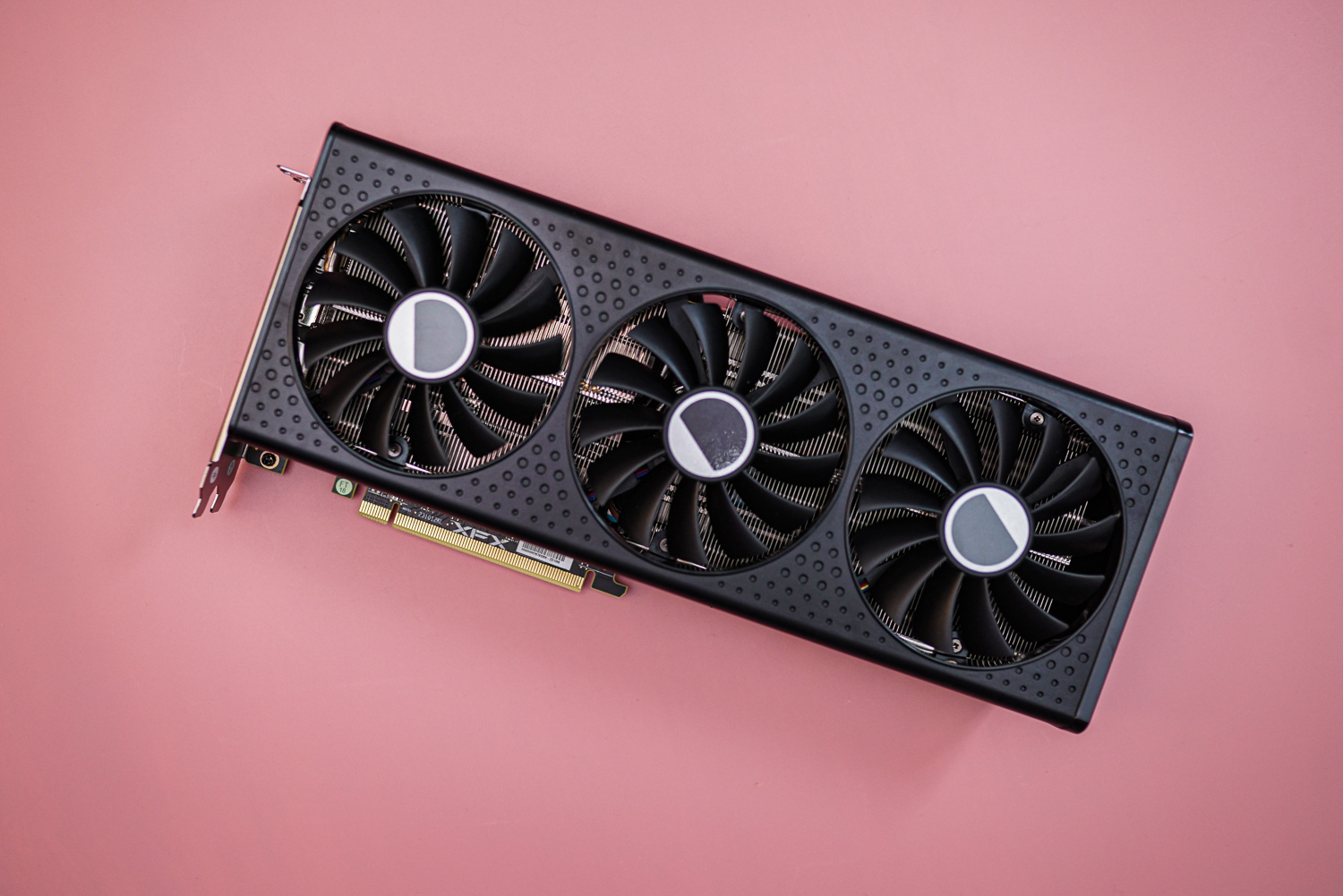 The RX 7600 XT graphics card on a pink background.