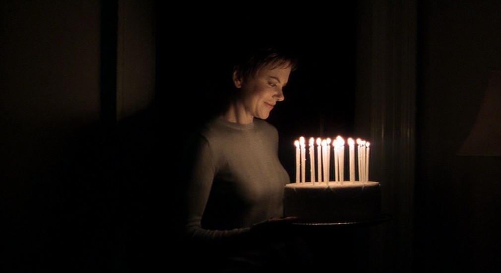 A woman holds a birthday cake in Birth.