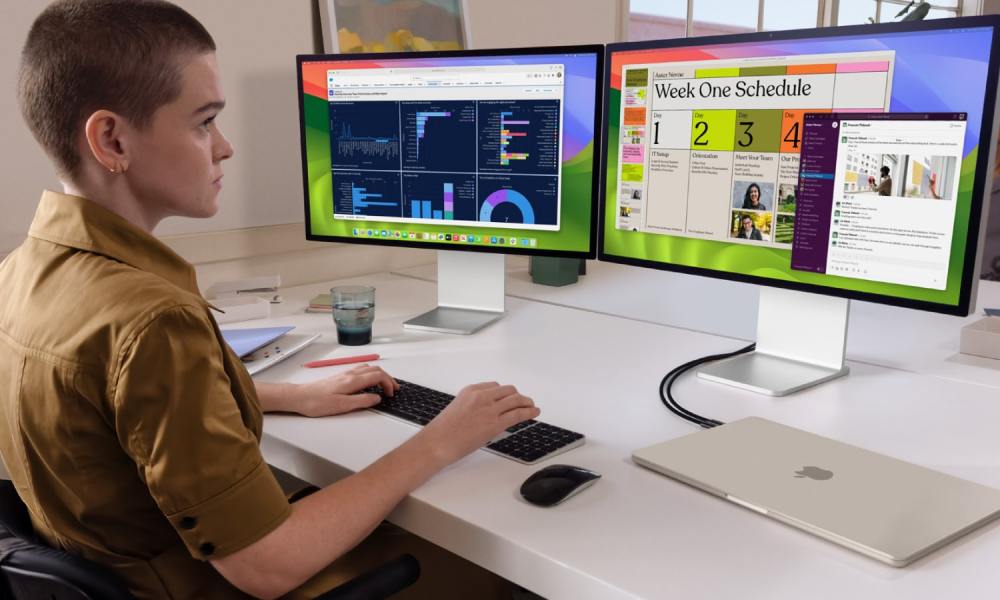 A person using a MacBook Air connected to two monitors.