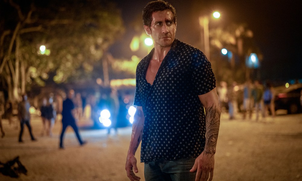 Jake Gyllenhaal stands in a parking lot in Road House.