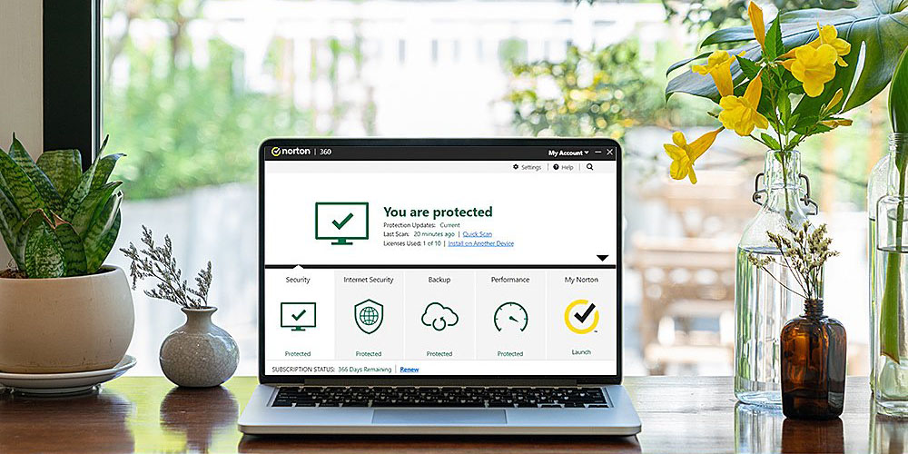 Someone using Norton 360 Premium on a laptop by a window.