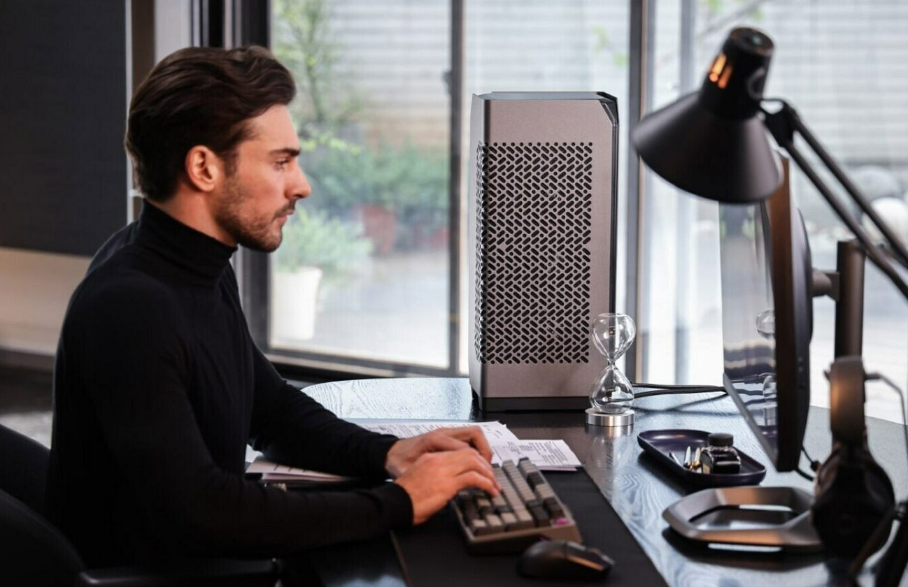 A person setting at a desk with the Cooler Master Ncore 100 Max case.