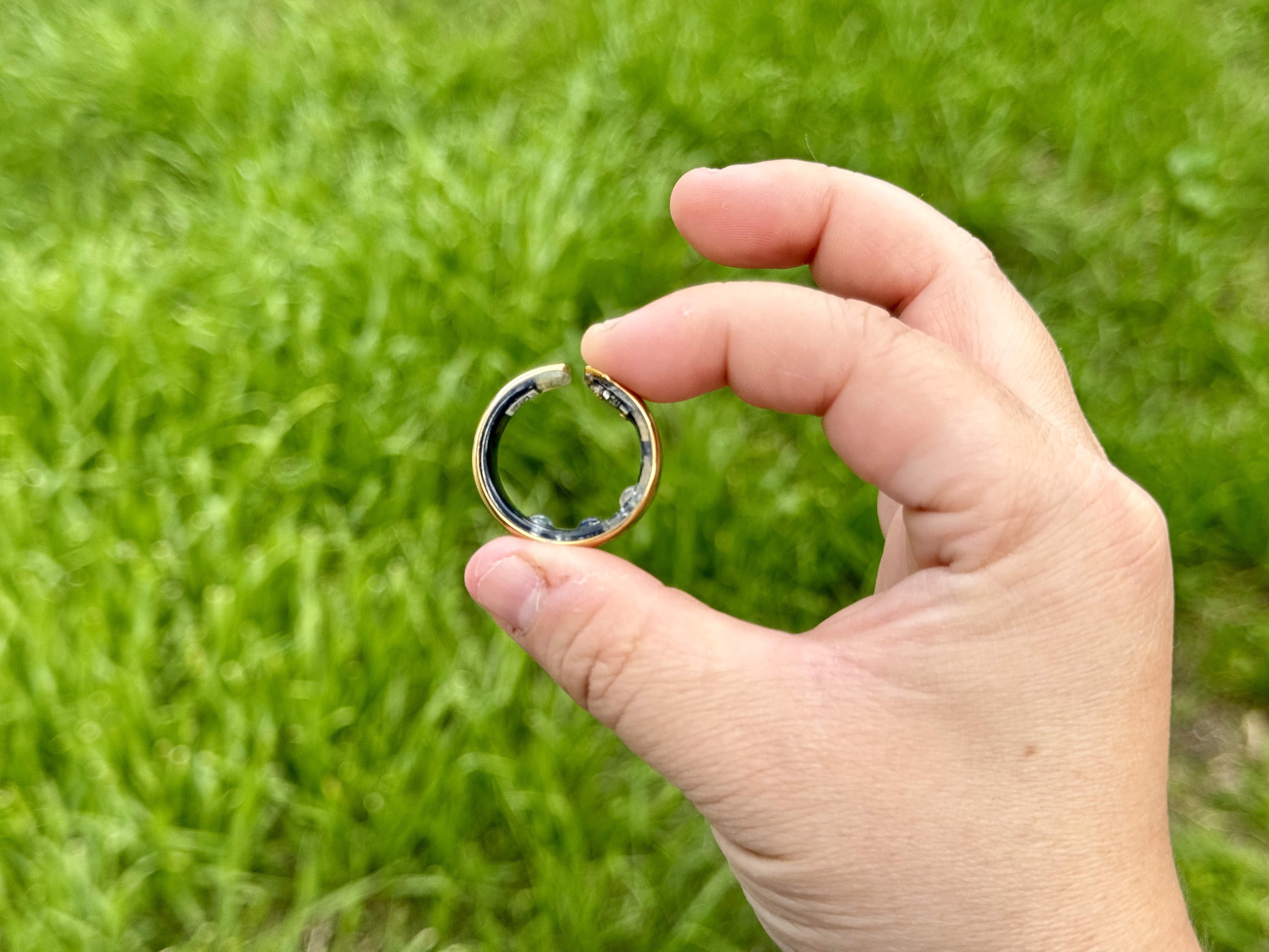 Movano Evie Ring in gold held with two fingers.