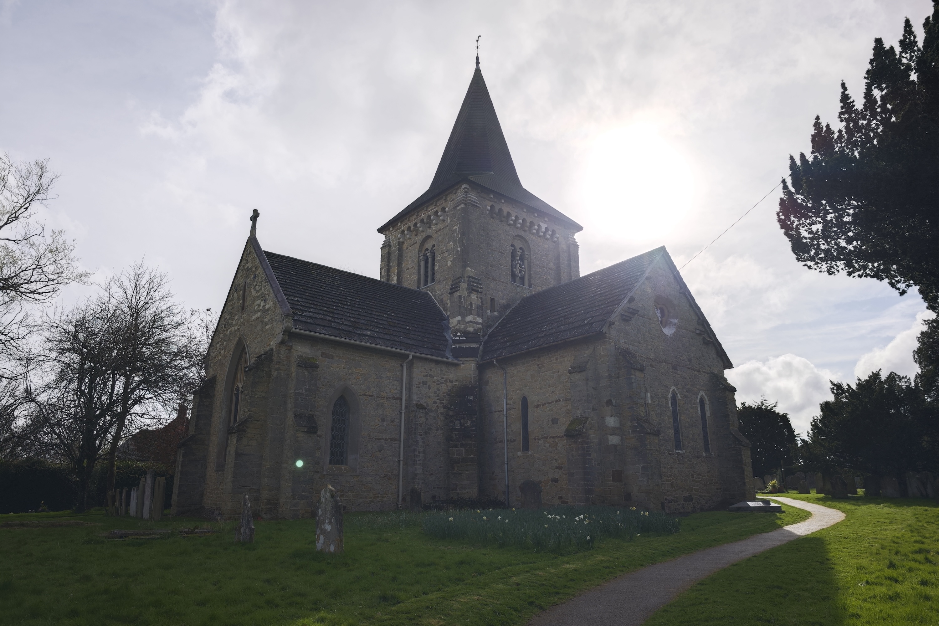 A photo of an orb floating over a gravestone in a churchyard.