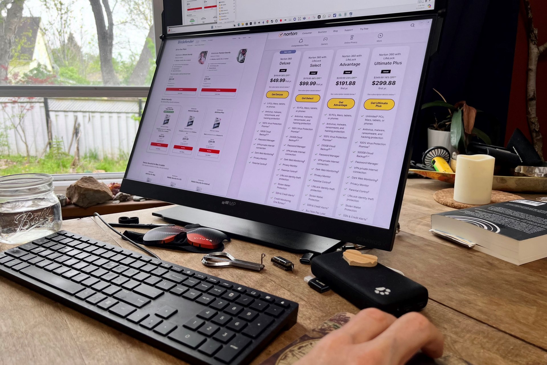 A person compares Bitdefender and Norton antivirus software pricing on a Windows PC.