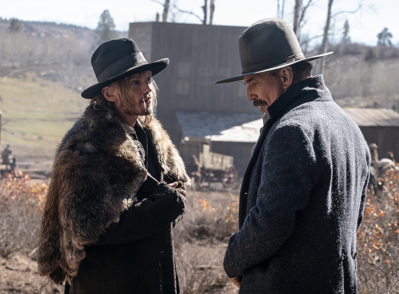 Two men in Cowboy hats stand across from each other and talk.