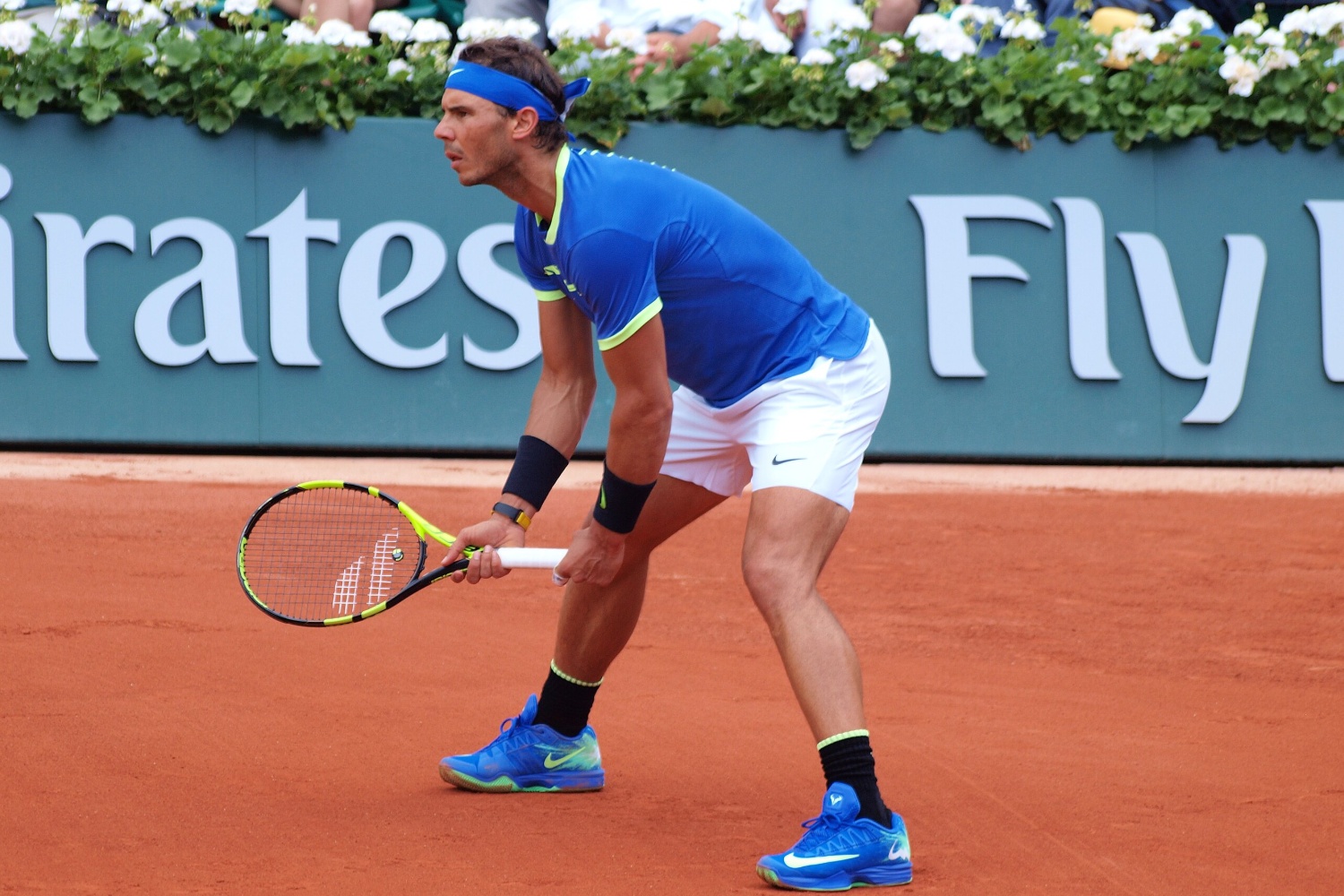 Rafael Nadal stands with his racket and prepares to hit a tennis ball.