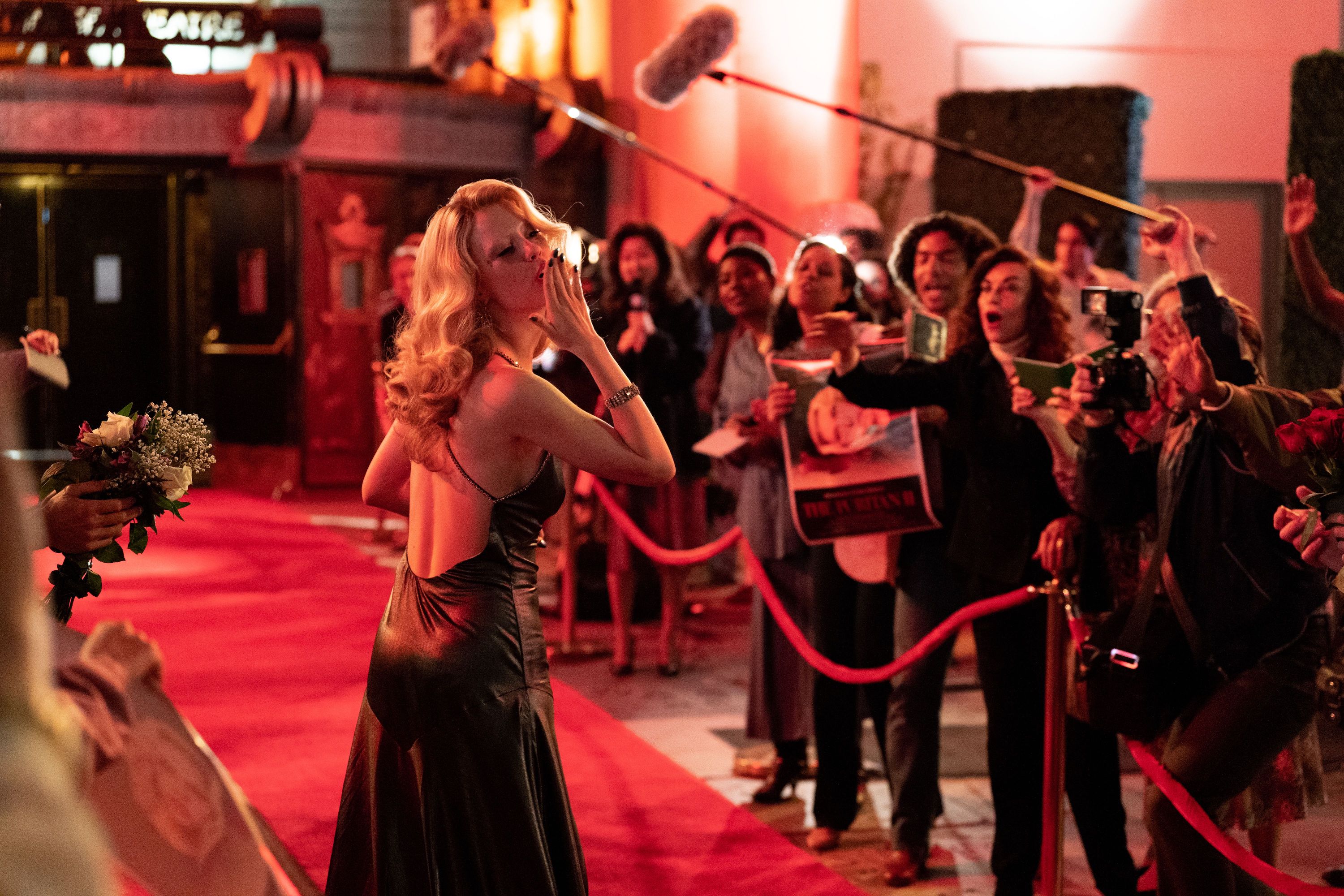 A woman walks the red carpet and blows a kiss.