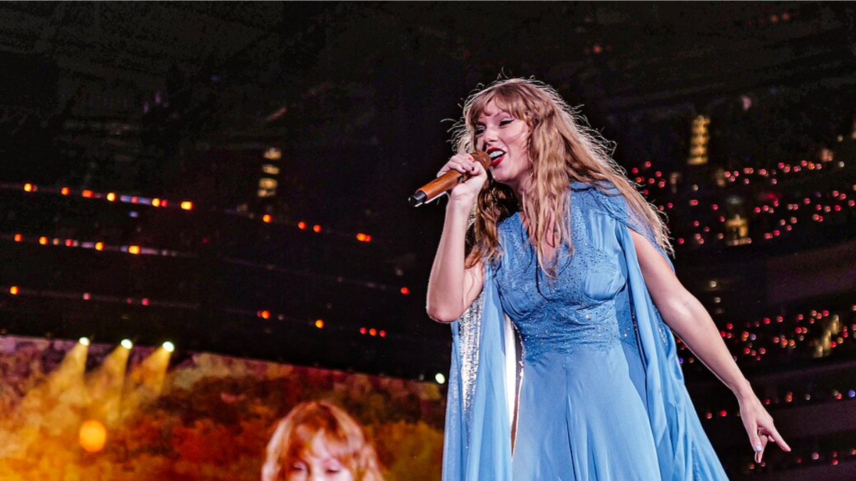 Taylor Swift holds a microphone and sings.