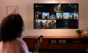 A woman holding a remote while looking at an Amazon Fire TV with the Xbox app on it. It's on the Cloud Gaming menu with Fallout 76, Senua's Saga Hellblade 2 and more on it.