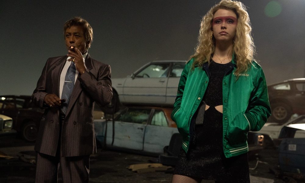 Giancarlo Esposito and Mia Goth stand in a junkyard together in MaXXXine.