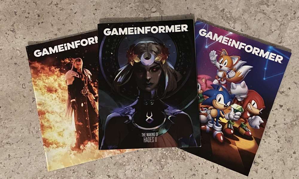 Three Game Informer magazines are spread out on a marble surface. Games featured on covers (from left): Final Fantasy 7 Rebirth, Hades 2, and Sonic Superstars.