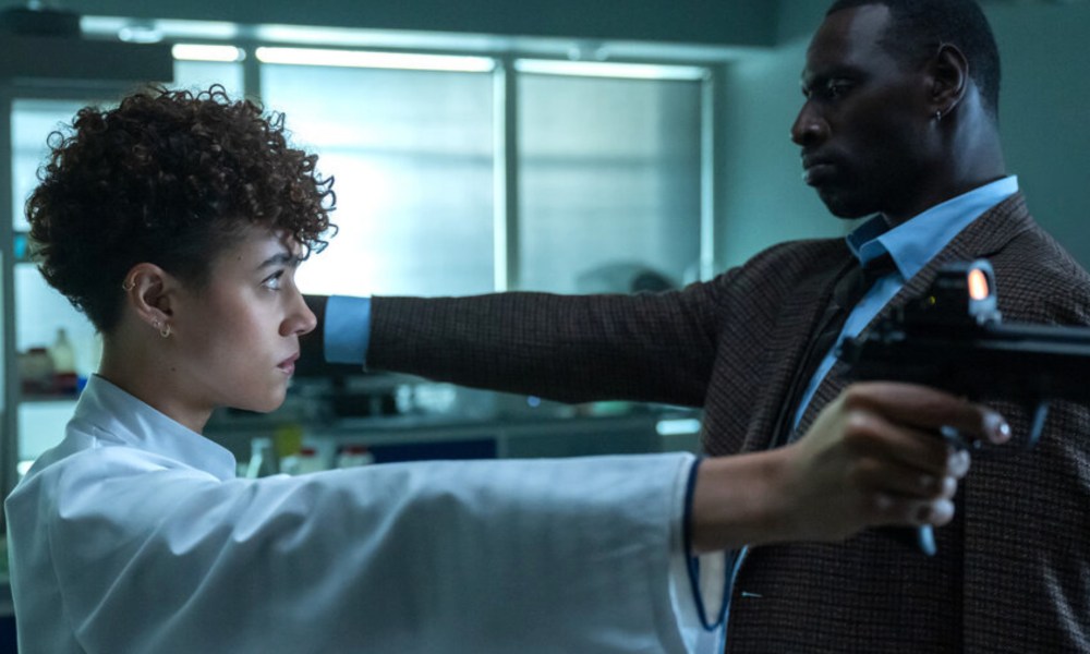 Nathalie Emmanuel and Omar Sy face each other with guns in The Killer.