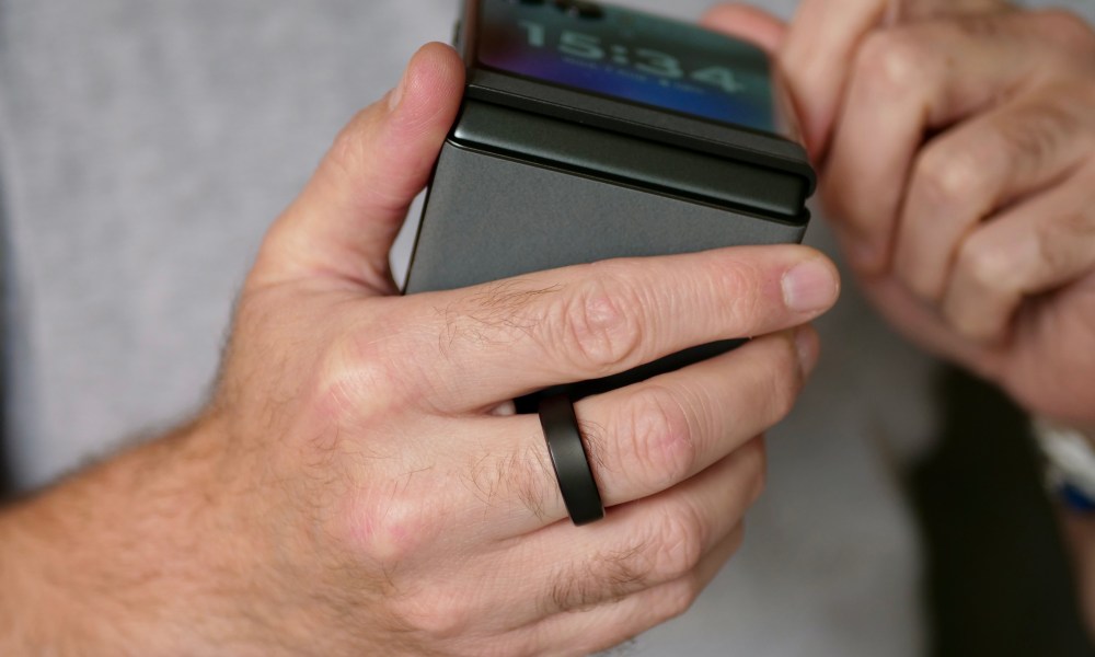 A person wearing the RingConn Gen 2 and holding a phone.