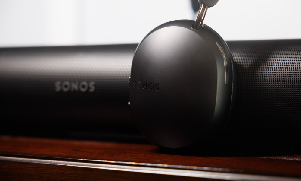 The Sonos Ace headphones in front of the Sonos Arc soundbar.