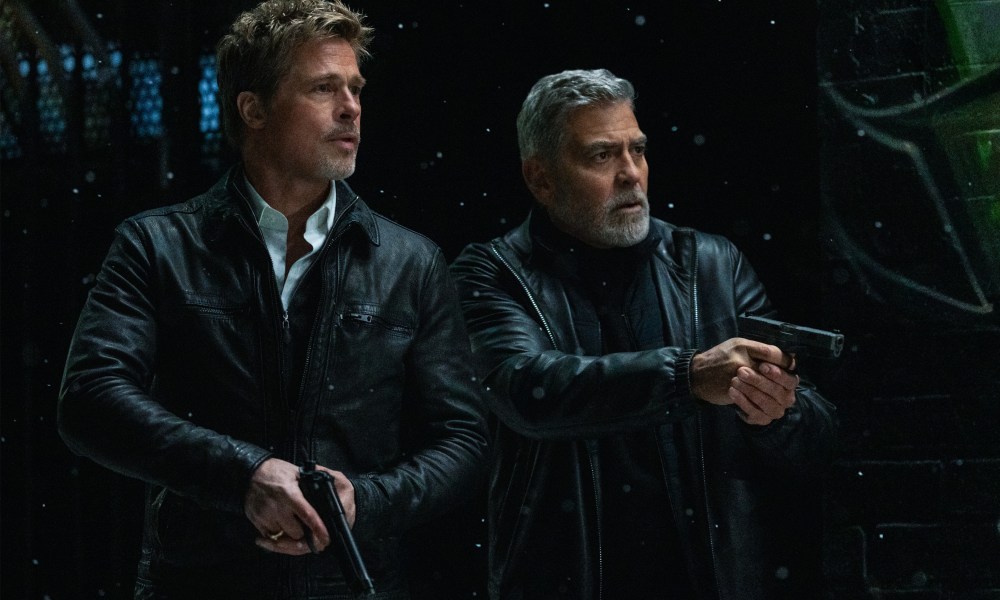 Brad Pitt and George Clooney hold guns in Wolfs.