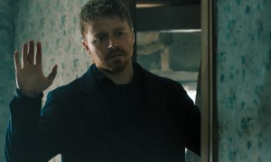 Jack Lowden stands in a doorway with his hands raised in Slow Horses season 4.