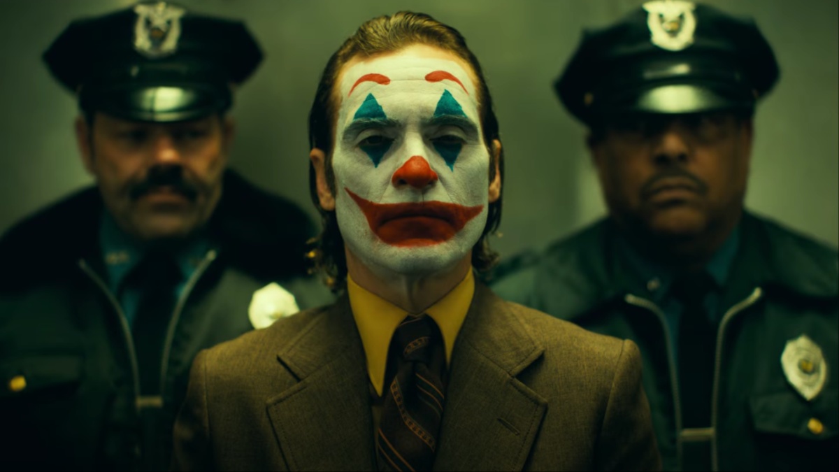 A clown stands in front of two cops in an elevator.