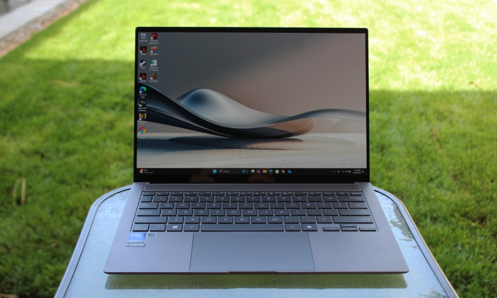 The Zenbook S 14 on a table in front of a grass lawn.