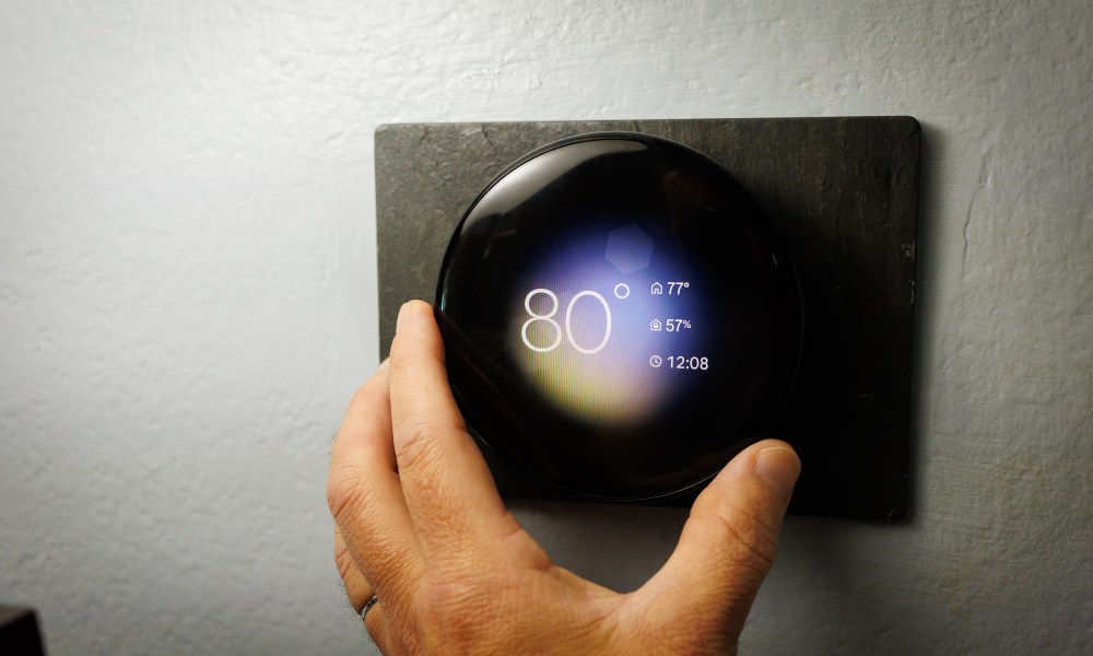 A hand turning the Nest Thermostat.