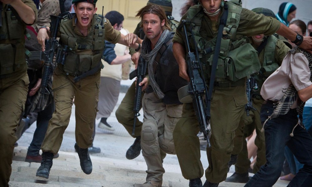 Brad Pitt runs down a street with soldiers.