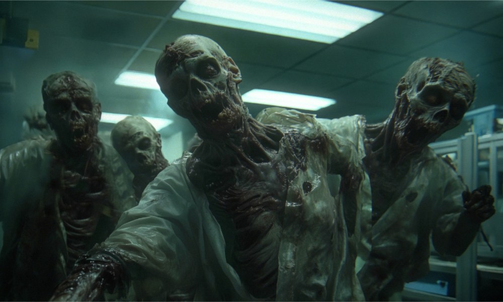 A group of zombies looking to attack walk toward camera.