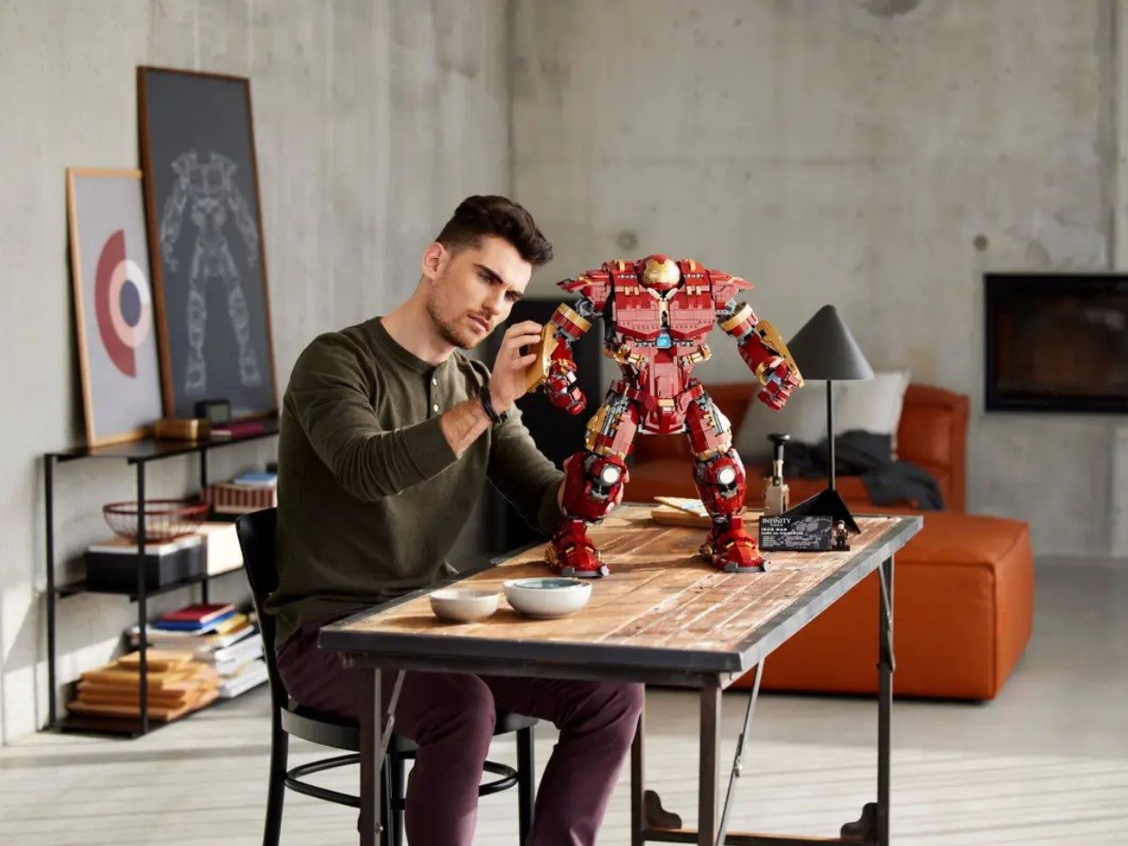 A young man assembles a Lego Hulkbuster toy.