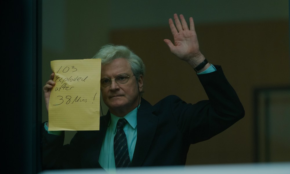 A man holds his hand up with a paper against glass.