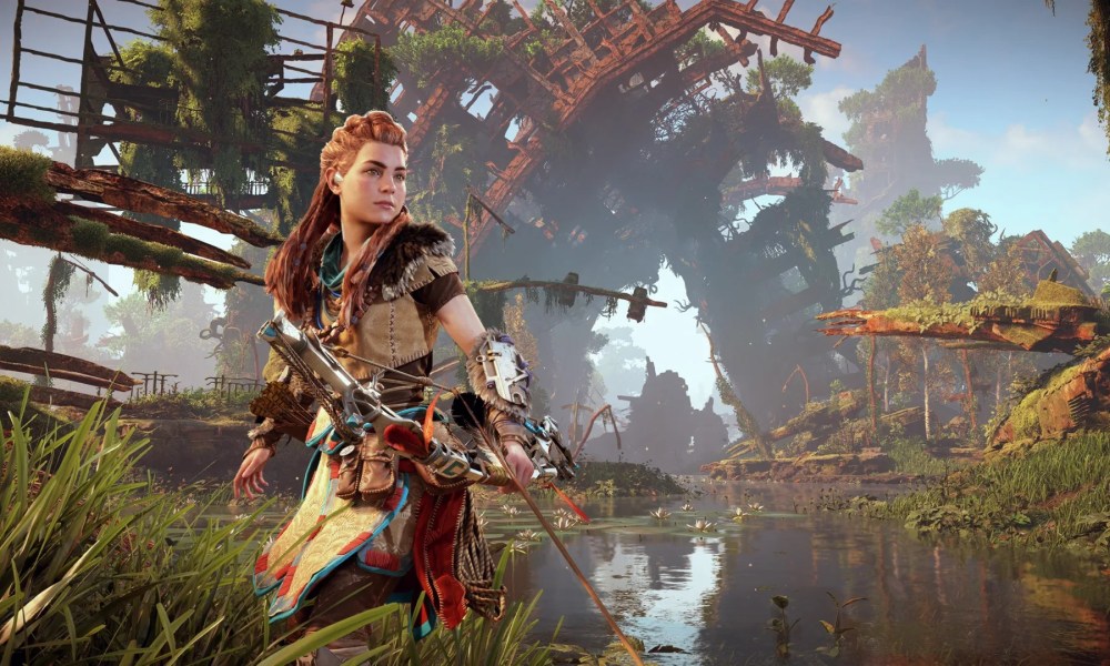 Aloy standing in knee-deep water with her bow and arrow in front of some ruins.